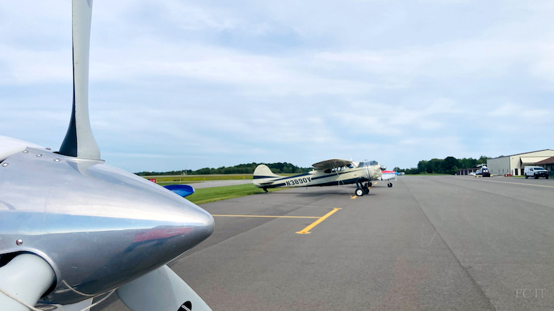Closeup on prop and looking at parked planes and main Airport building in background.